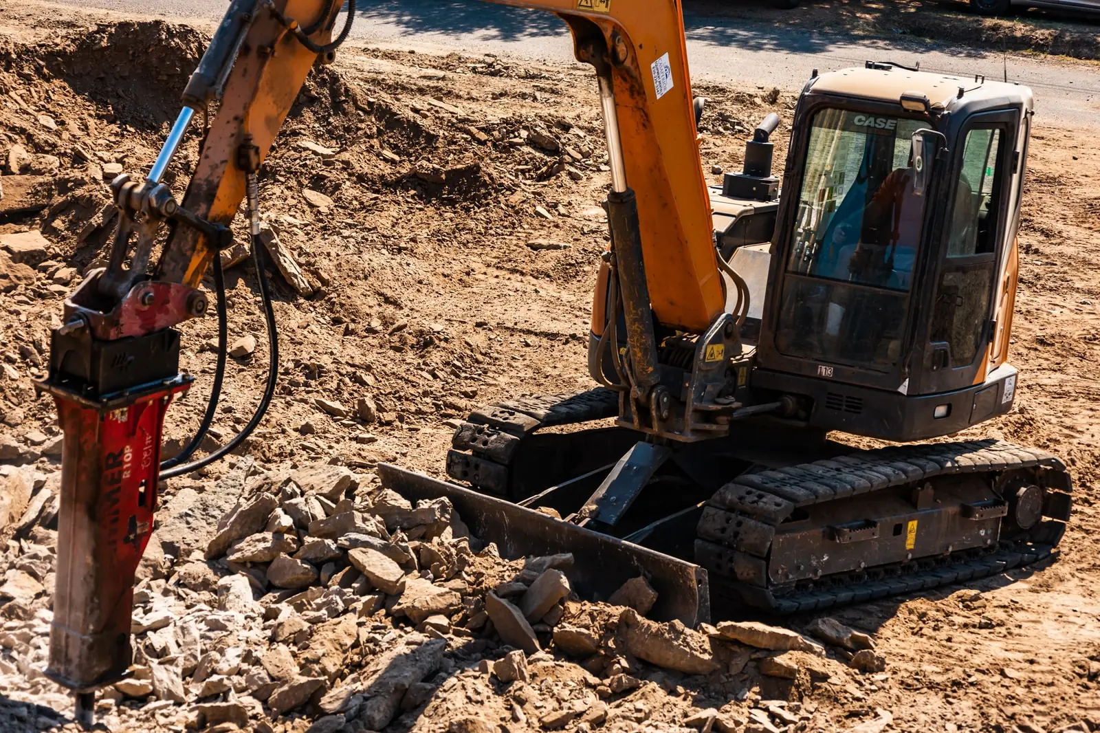 Excavator with a hydraulic breaker working limestone ledges