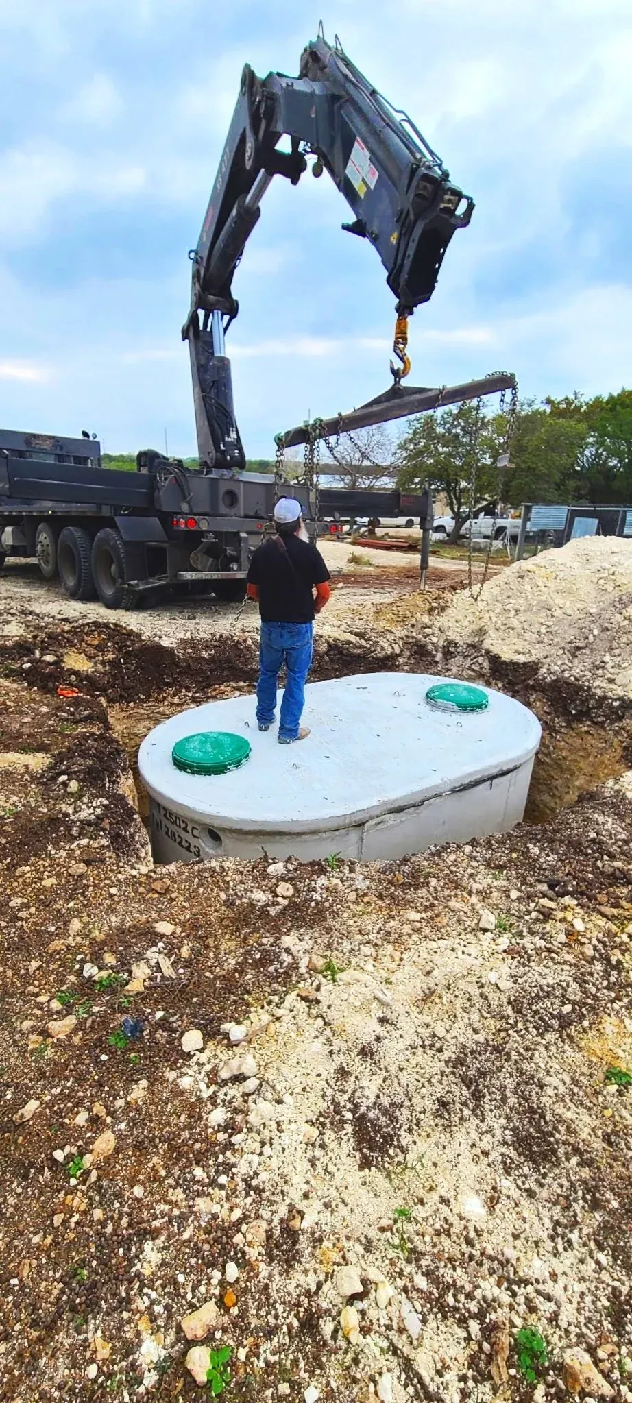 Septic tank being lowered into place by a boom truck